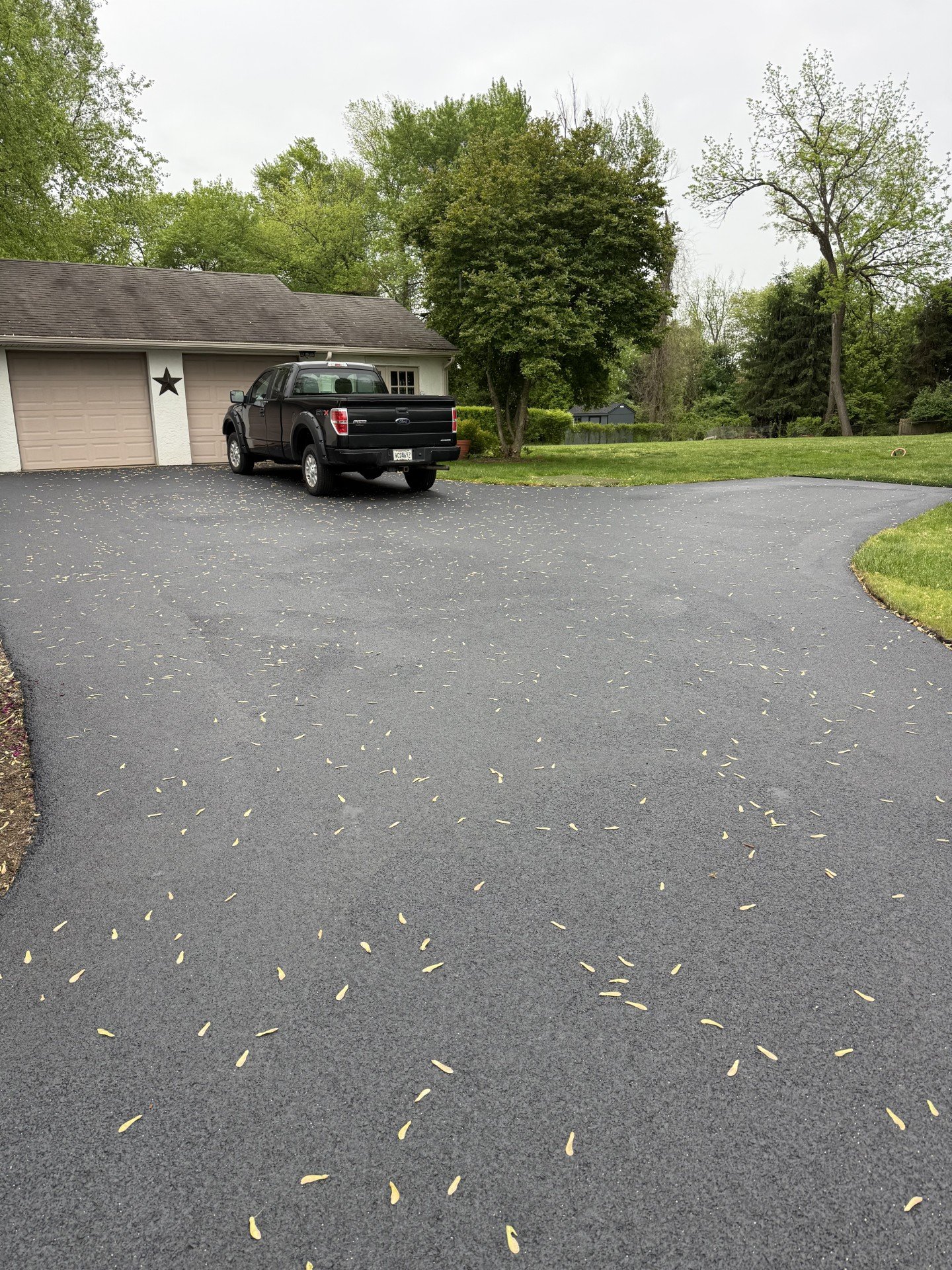 Wide sealcoated driveway with pickup truck parked at garage